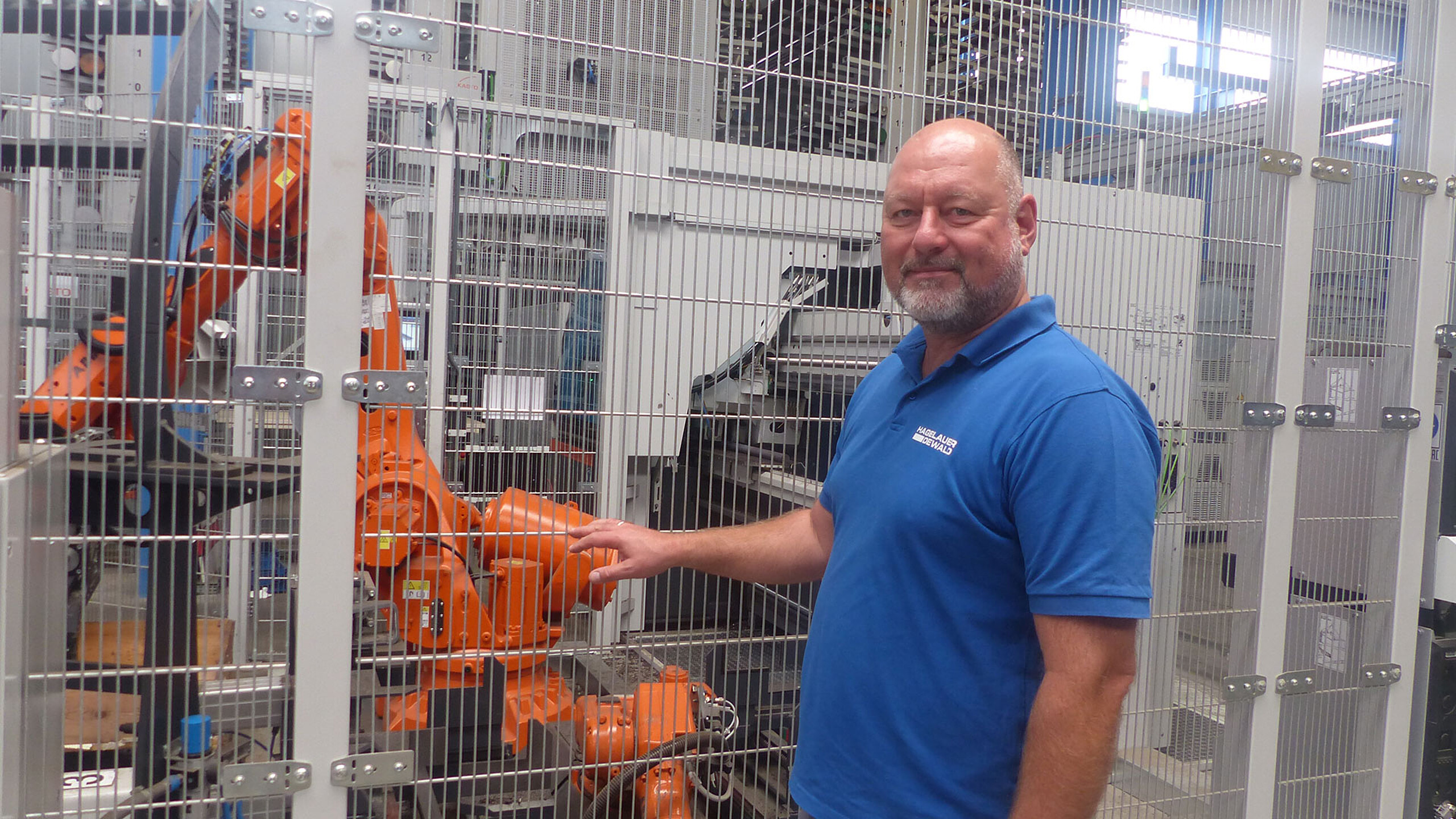 Industrieroboter in gesicherter Fertigungszelle mit Bedienpersonal